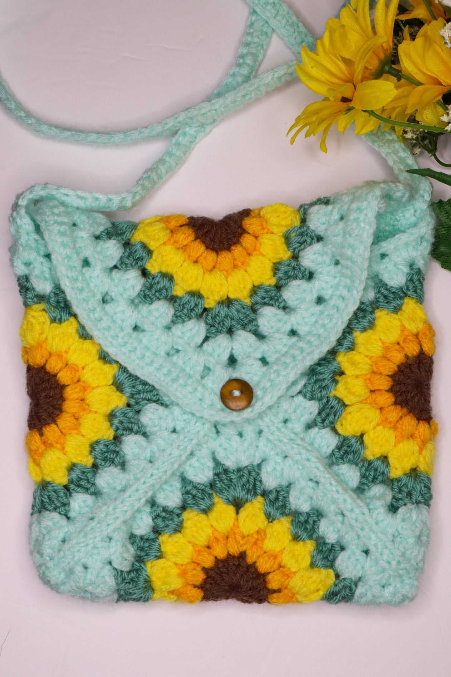 Crocheted bag with sunflower patterns on a light pink background