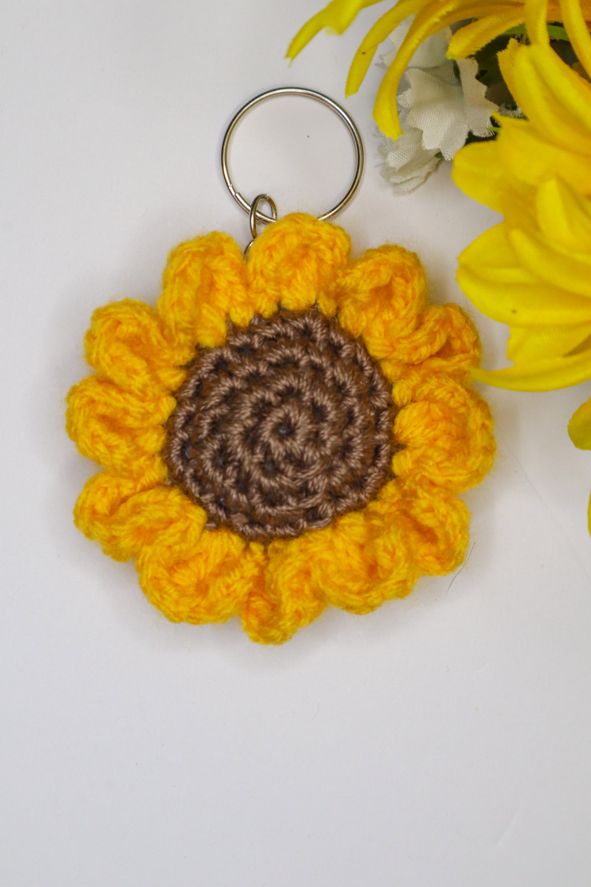 Crocheted sunflower keychain with brown center on a white background