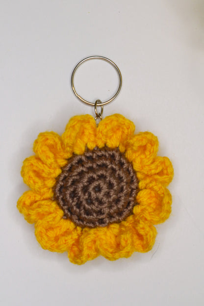 Crocheted sunflower keychain with yellow petals and brown center on a white background