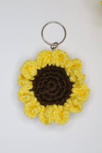Crocheted sunflower keychain with yellow petals and brown center on a white background