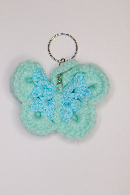 Crocheted butterfly keychain with a light blue center on a white background