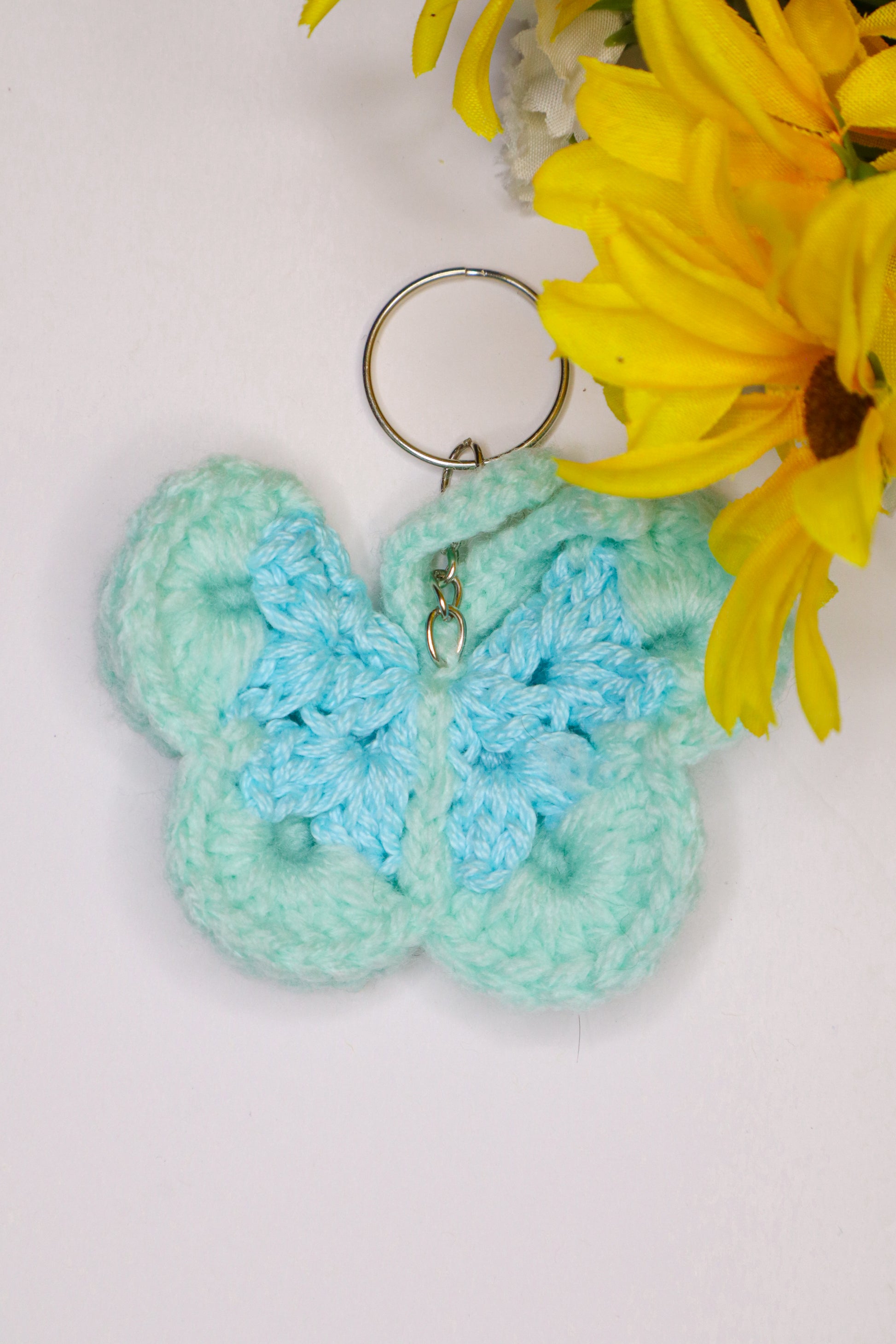 Crocheted butterfly keychain with a yellow flower on a light background