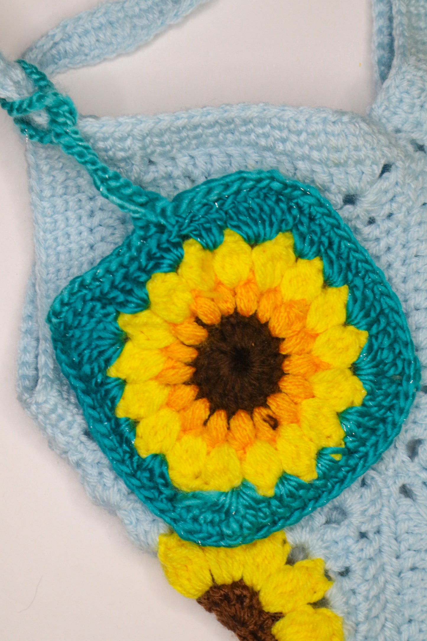 Crocheted bag with a sunflower design on a light blue background