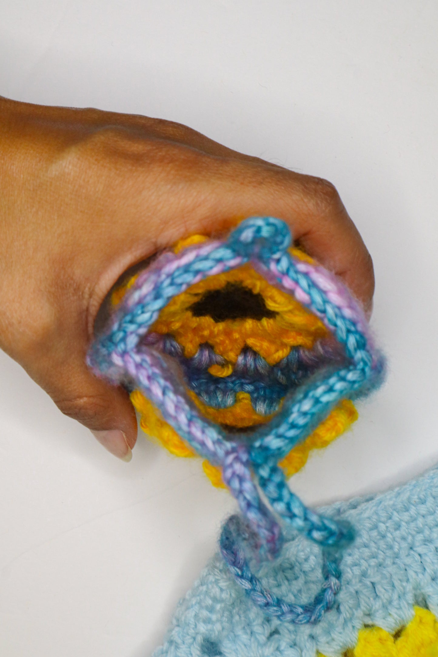 Colorful knitted item held by a hand against a white background
