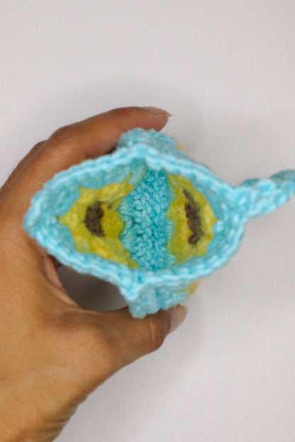 Hand holding a blue and yellow textured object against a white background